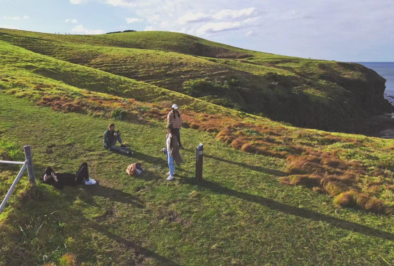 Individuals gathered on vibrant green cliffs overlooking the ocean—representing Roooll's commitment to human dignity.